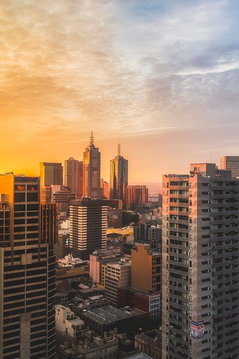 Stunning view of Melbourne's skyline at sunset, capturing modern skyscrapers and warm sky.